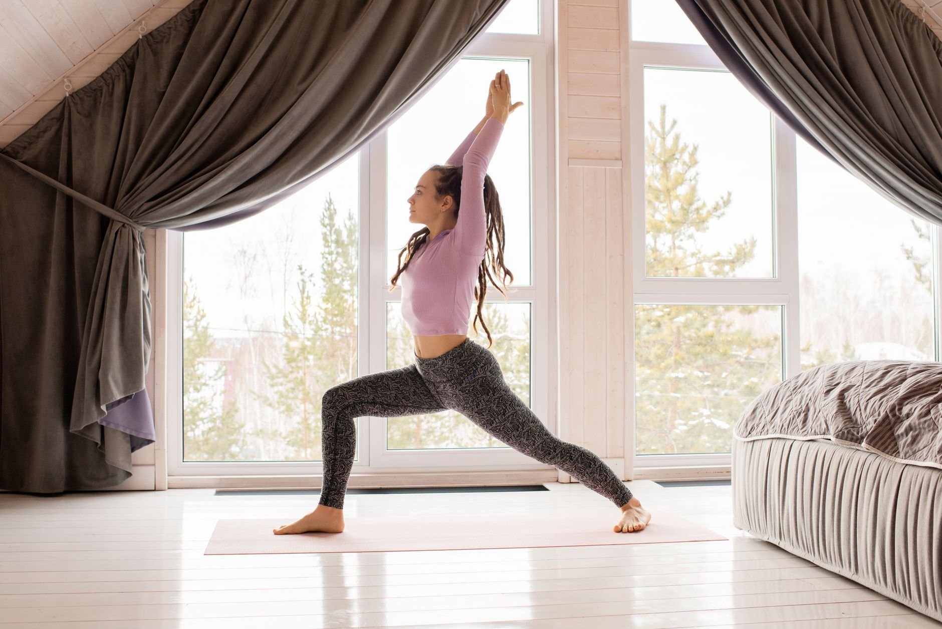 A woman performing a yoga pose on a mat indoors with natural light.